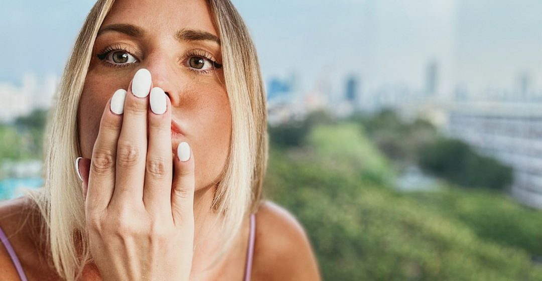 Perempuan melindungi wajah dengan tangan dalam cahaya matahari