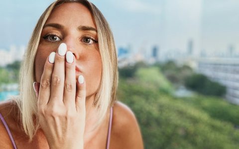 Perempuan melindungi wajah dengan tangan dalam cahaya matahari
