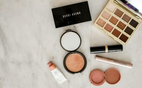 Aneka produk makeup di atas permukaan abu-abu